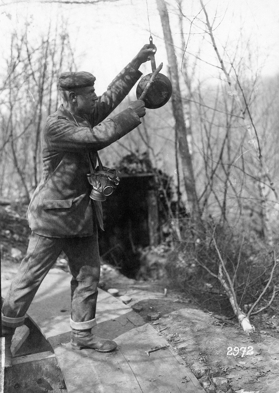 With no bell available, a German stationed between Rheims and Laon in May 1917 uses a handy frying pan to signal a gas attack. The clang of metal on metal is still one of the standard alarms when warning of an impending chemical or biological attack. (National Archives)