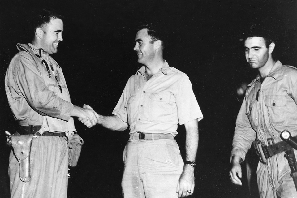 A relieved Maj. Sweeney (center) greets Col. Tibbets back on Tinian. (National Archives)
