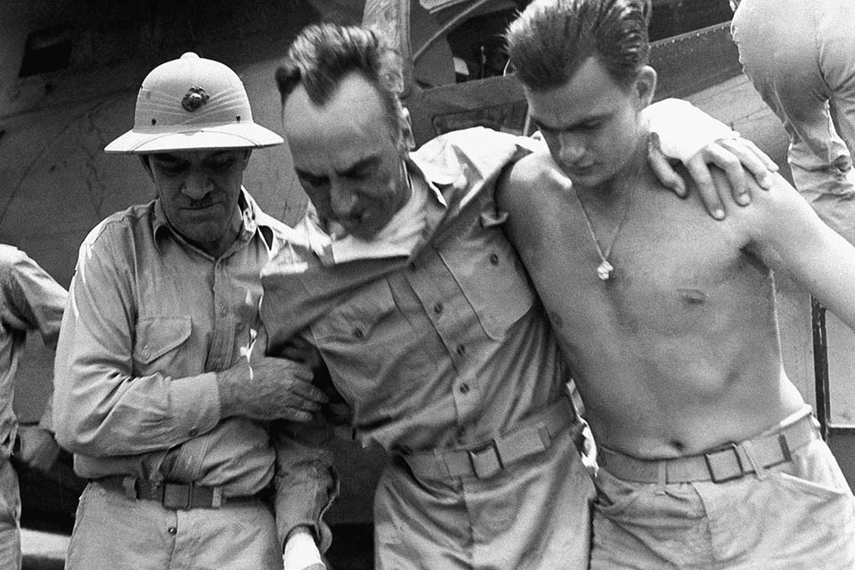 Rickenbacker, center, is helped to a jeep by Col. Robert L. Griffin, Jr., left, and an unidentified member of the rescue plane's crew, after being flown to a South Pacific base following his rescue after 22 days afloat in a rubber raft. (National Archives)
