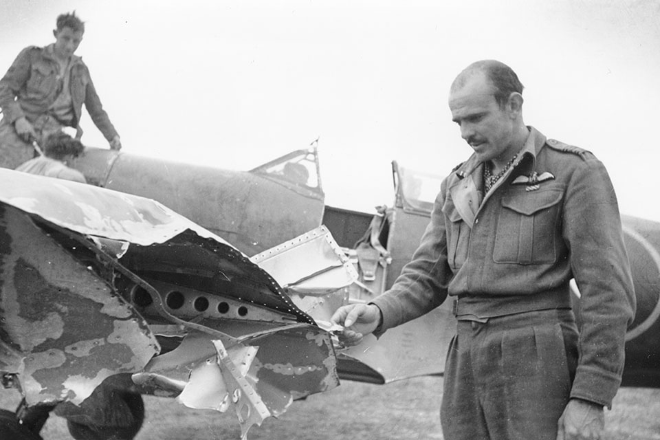 Squadron Leader Wade checks the damage to his Spitfire, the result of a close call in North African skies. (IWM CNA 809)