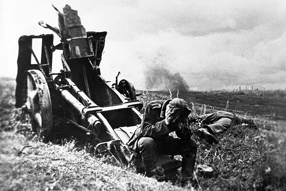 Head bowed in shock, a German soldier at Kursk sits on a destroyed artillery gun, near the body of a slain comrade. (Sovfoto/Universal Images Group via Getty Images)