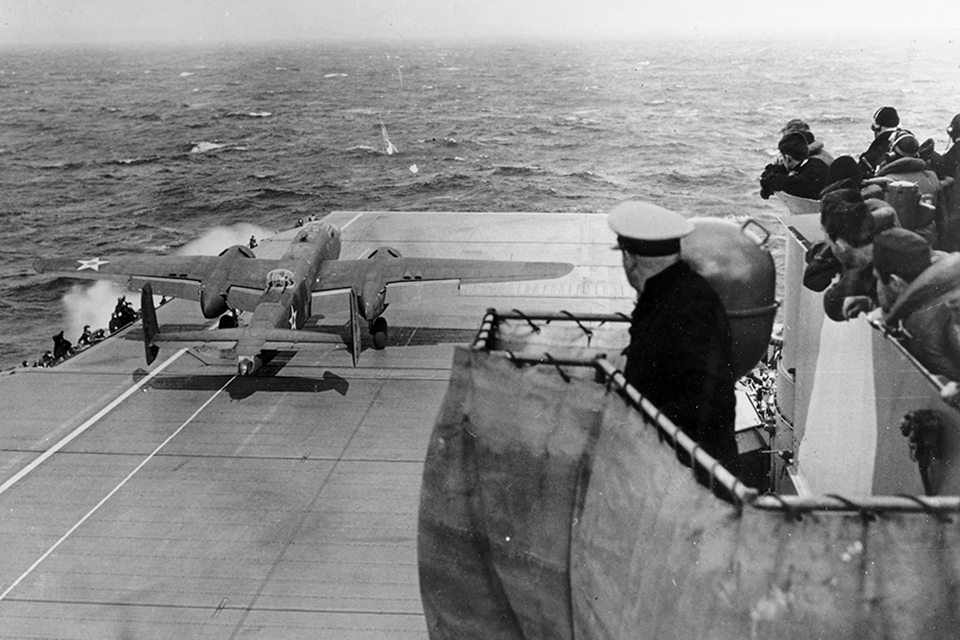 The first to launch from the carrier Hornet Lt. Col. James Doolittle led the mission. Observing from the bridge is the carrier's "Skipper" Capt. Marc A. Mitscher. (National Archives)