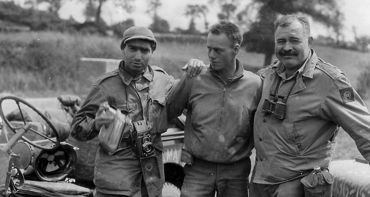 LIFE Photographer Robert Capa (left) and author Ernest Hemingway (right) pose with their driver (center) near Pont Brocard, France. The pair accompanied elements of the 2nd Armored Division during the COBRA breakout.