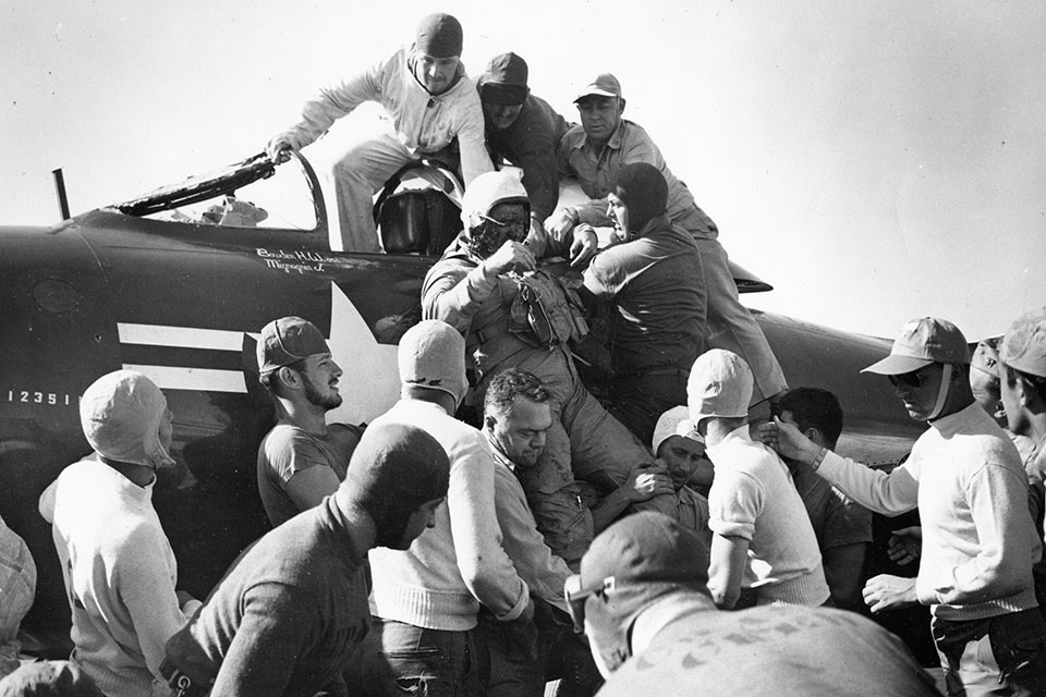 Crewmembers lift a bloody Jackson out of the cockpit of his jet. (National Archives)