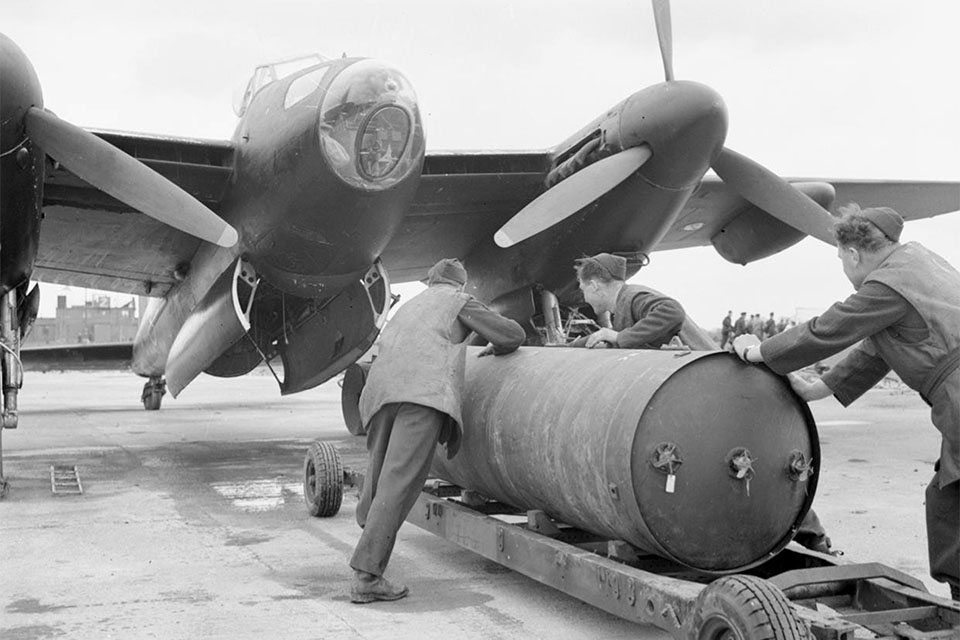 Armorers load a 4,000-pound HC “cookie” bomb on a modified night bomber of No. 692 Squadron. The Squadron was part of the Light Night Striking Force of No. 8 (PFF) Group, which specialised in fast, high-flying night raids on Germany. (IWM