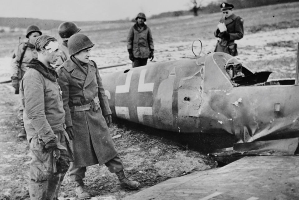 A dejected 22-year-old Alfred Michel of Jagdgeschwader 53 surveys the remains of his downed Messerschmitt Me-109G-14, surrounded by soldiers of the 90th Infantry Division. It was Michel's first and last combat sortie. (National Archives)