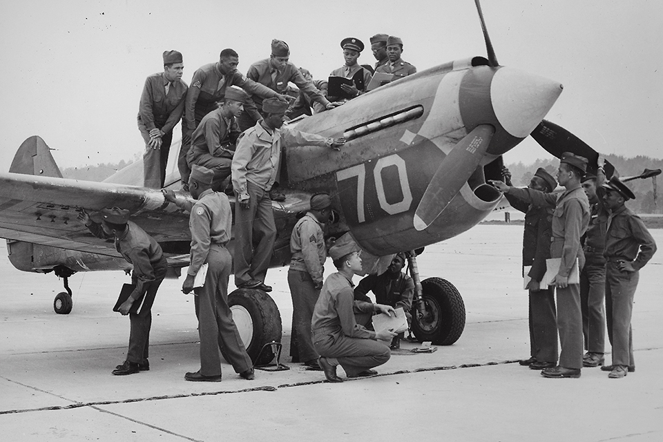 Tuskegee students pore over one of the school's Curtiss P-40 fighters.
