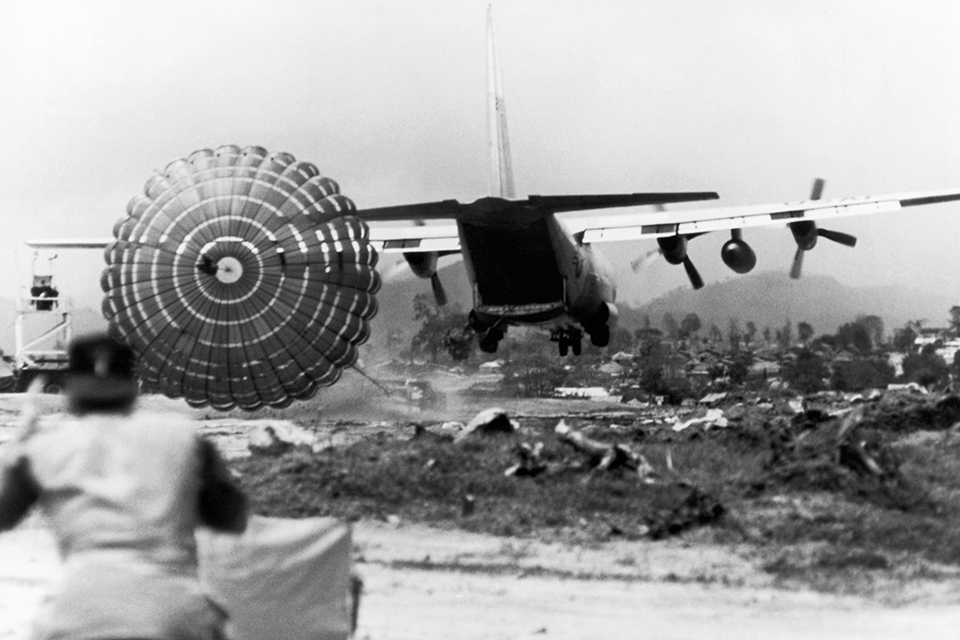A C-130 Hercules delivers supplies using the Low Altitude Parachute Extraction System (LAPES) at an embattled airstrip near, An Khe, Vietnam, May 1966. (Underwood Archives/Getty Images)
