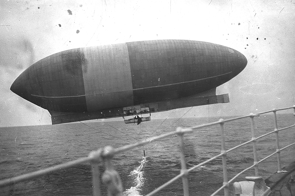 A view of “America” from “Trent’s” deck. Note the airship’s “equilibrator,” the cable intended to regulate altitude, trailing below in the water. (Library of Congress)