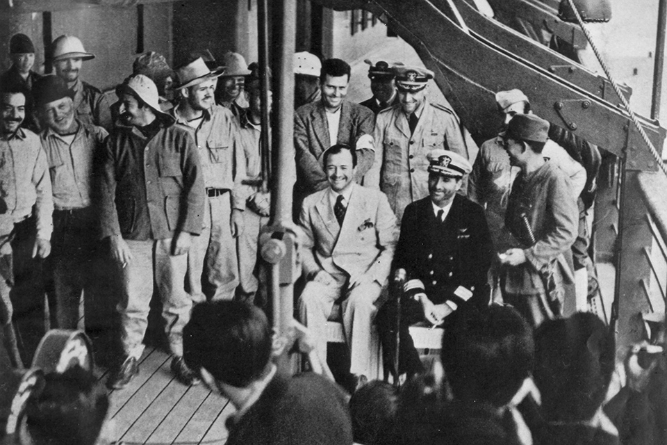 Smiling for the Japanese propaganda cameras some of the Wake island defenders, now POWs aboard the transport ship Nitta Maru. Commander Winfield Scott Cunningham, seated in the dark uniform would be awarded the Navy Cross for his leadership. (National Archives)