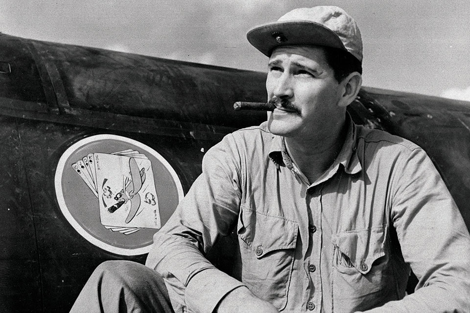 Major Foss poses beside the emblem of his new command, VMF-115, on June 1, 1944. (AP Photo)