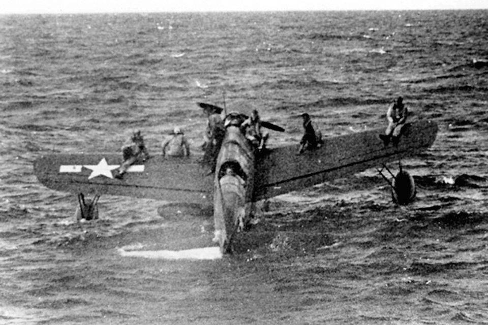 Rescued airmen perch on the wings of Lieutenant John Burns’ OS2U-3 off Truk in 1944. (U.S. Navy)