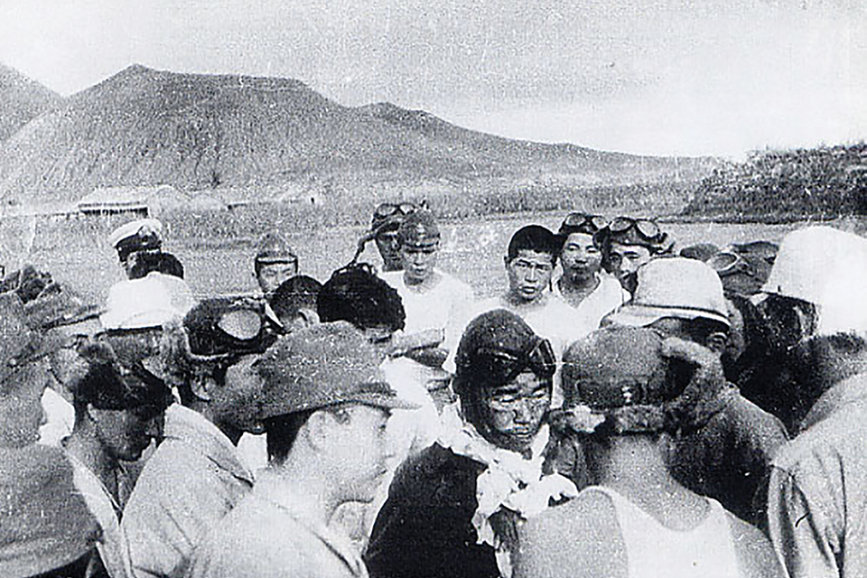 After his narrow escape from Guadal­canal on August 7, Sakai, surrounded by airfield personnel, gives his mission report before going to the hospital. (HistoryNet Archives)