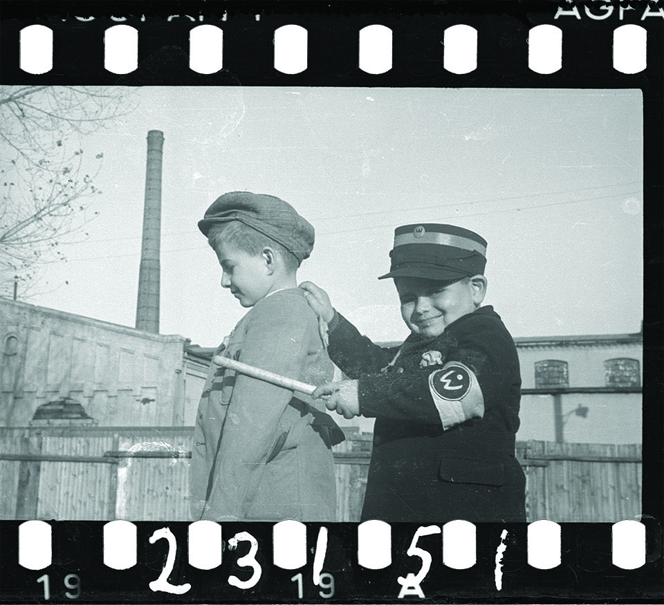 CHILD’S PLAY: Jewish children (top, right) engage in a game with sinister undertones. In a scaled-down uniform of the ghetto’s Jewish police, one child pats down a mini-deportee. Actual Jewish police often were criminals the Germans recruited to maintain order in the ghetto. 