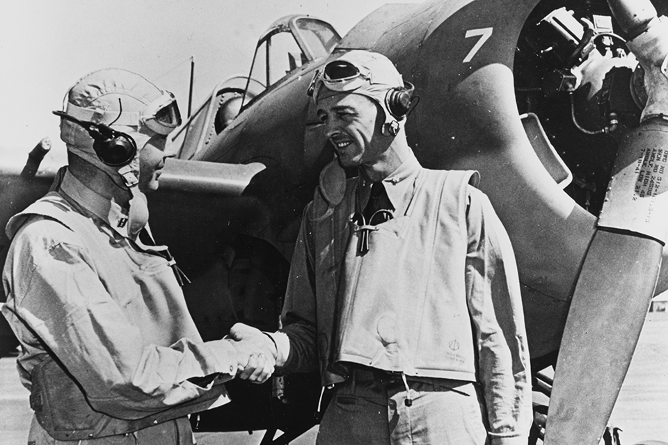 O'Hare, (left) shaks hands with his squadron commander, Lt. Cmdr. John S. Thach, in front of a Grumman F4F Wildcat at an Oahu air base after their action at Rabaul. (U.S. Navy)