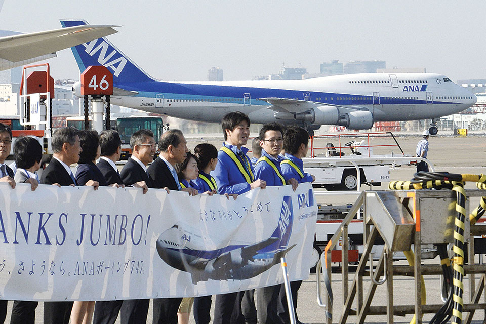 On March 31, 2014, All Nippon Airways employees hold a banner saluting the last 747 to arrive in Tokyo, ending four decades of jumbo jet service by Japanese carriers. (Kyodo News via Getty Images)