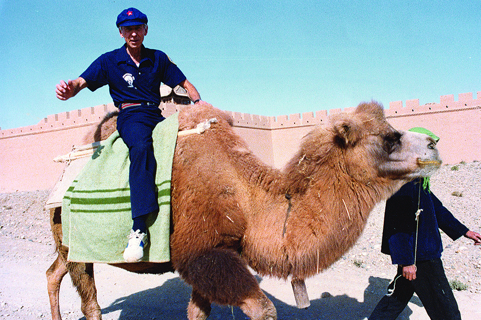 Back in China, Scott sports a red-starred cap as he rides a Bactrian camel at the Great Wall. (Museum of Aviation)