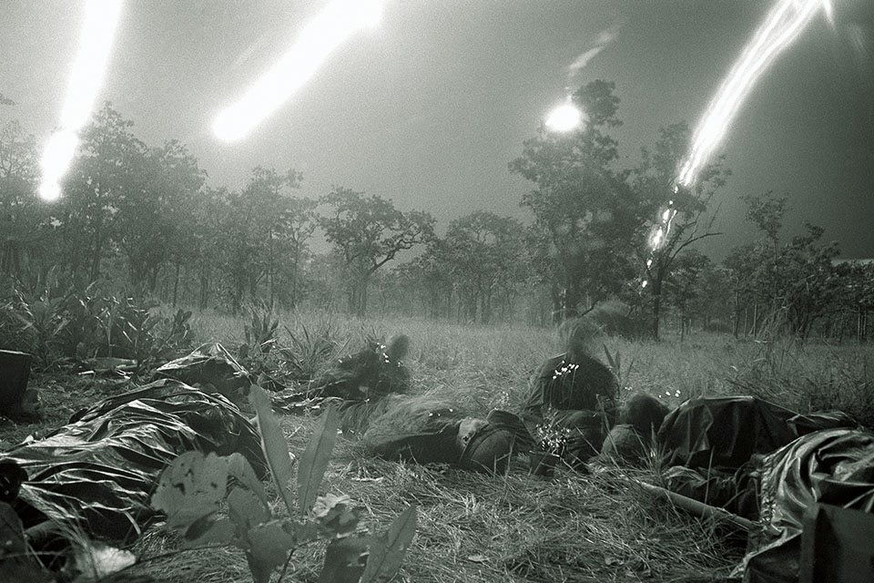 Troops of the 1st Air Cav, ambushed at Landing Zone Albany on Nov. 17, lie in a field illuminated by flares from aircraft. (AP Photo/Rick Merron)