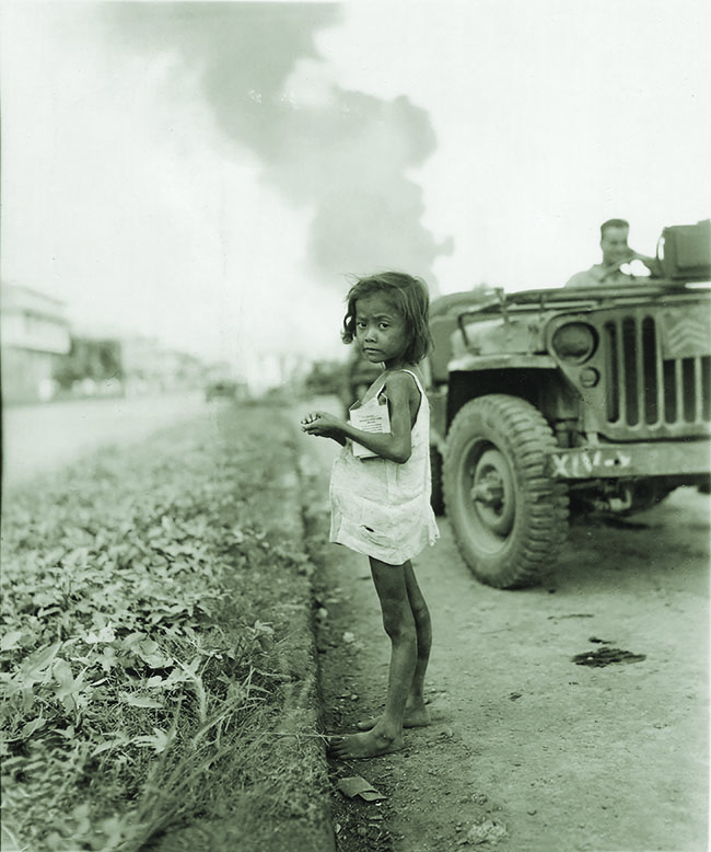 February 1945: a starving child in Manila clings to a box of U.S. Army rations. As many as 500 people starved to death daily on the eve of the battle.