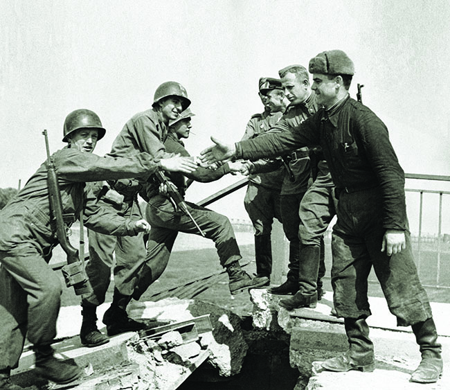 American and Soviet troops shake hands at a wrecked bridge over Germany’s Elbe River, April 26, 1945. (AP Photo)
