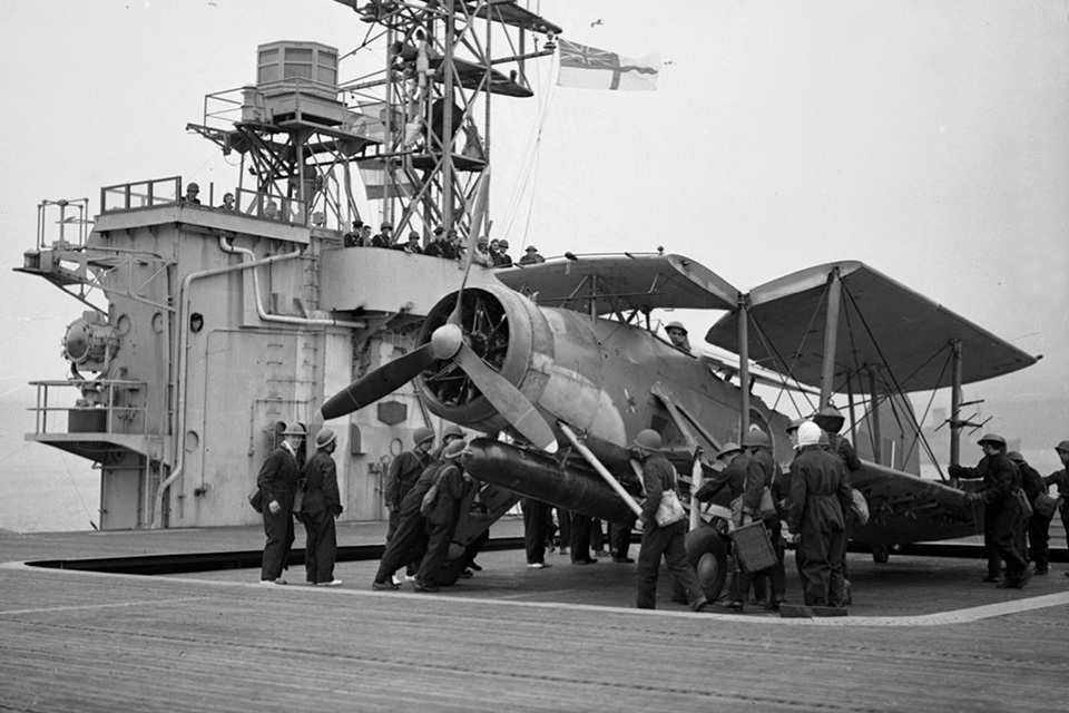 A Swordfish of No. 835 Squadron is lifted onto the flight deck of the escort carrier Battler for convoy escort duty in the North Atlantic on May 1, 1943. (Imperial War Museum A 16651)