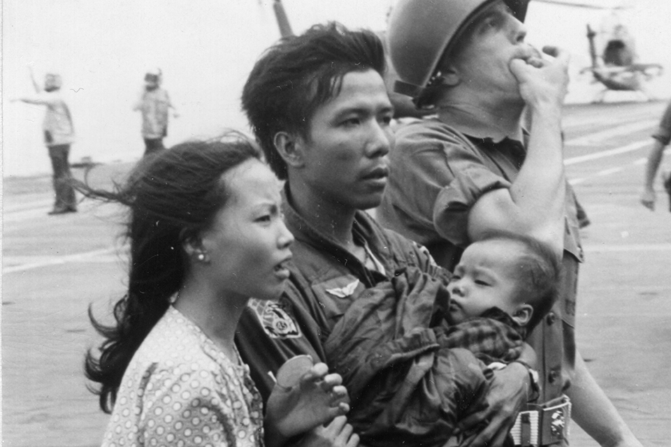 South Vietnamese Major Buang and his family are escorted by a Marine Security Guard across the deck of the USS Midway in one of the most dramatic moments during operation Frequent Wind. (PhotoQuest/Getty Images)