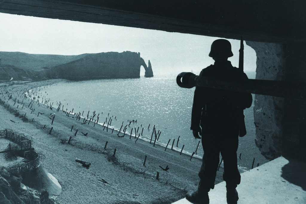 In a Wehrmacht propaganda photo, a German soldier surveys coastal beach defenses in northern France prior to D-Day. The Germans erected multiple barricades in anticipation of an amphibious Allied attack. BUNDESARCHIV, BILD 101I-299-1809-14/PHOTO: SCHECK 