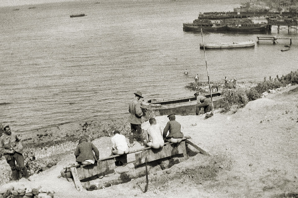 Four men use a beachside latrine at Gallipoli’s Anzac Cove in 1915. (Australian War Memorial)