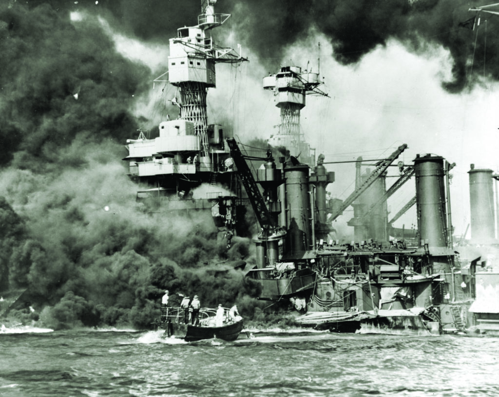 The USS West Virginia, with the USS Tennessee behind it, burns as its keel rests on the bottom of Pearl Harbor. (National Archives) 