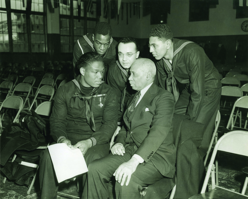 Miller speaks with sailors and a civilian at the Great Lakes, Illinois, Naval Training Station on January 7, 1943, as part of his war bond tour. (National Archives)