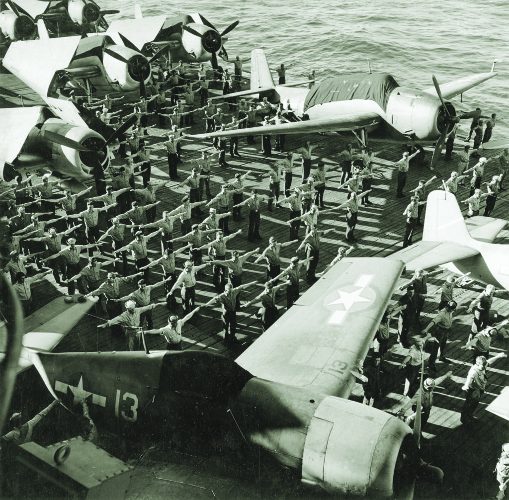 Elbow room is in short supply during a calisthenics session on the Yorktown. Avenger torpedo bombers appear at the top of the photo; Hellcat fighters at the bottom. (Charles E. Kerlee/U.S. Navy)