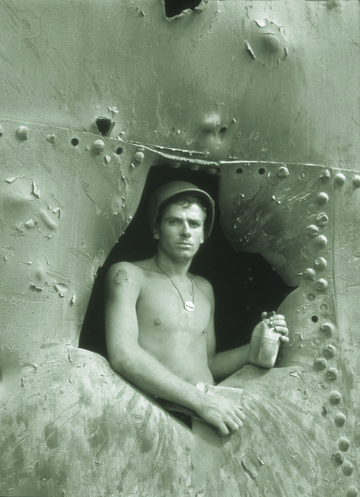 A marine peers out of a battered Japanese oil storage tank on Kwajalein Island in the central Pacific, a few weeks after Marine and U.S. Army forces successfully captured it in February 1944. (Charles E. Kerlee/U.S. Navy)