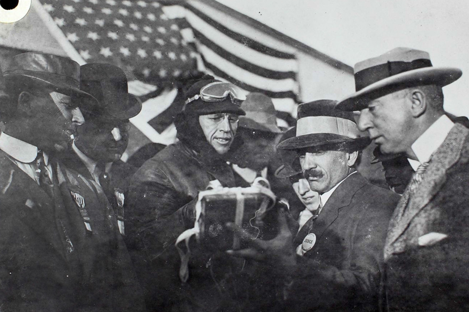 Hoxsey and officials examine his barograph after his record-setting flight to 11,474 feet on December 26, 1910. (Aviation History Collection/Alamy)