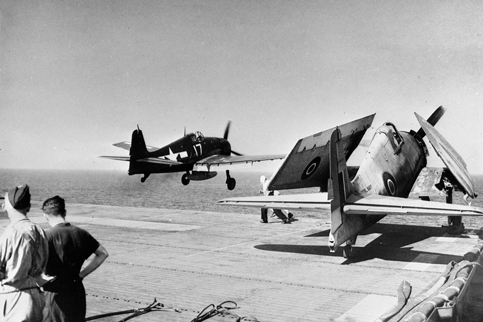 A visiting U.S. Navy F6F-5 departs Emperor while one of its own Hellcats waits its turn on deck. (IWM A25503)