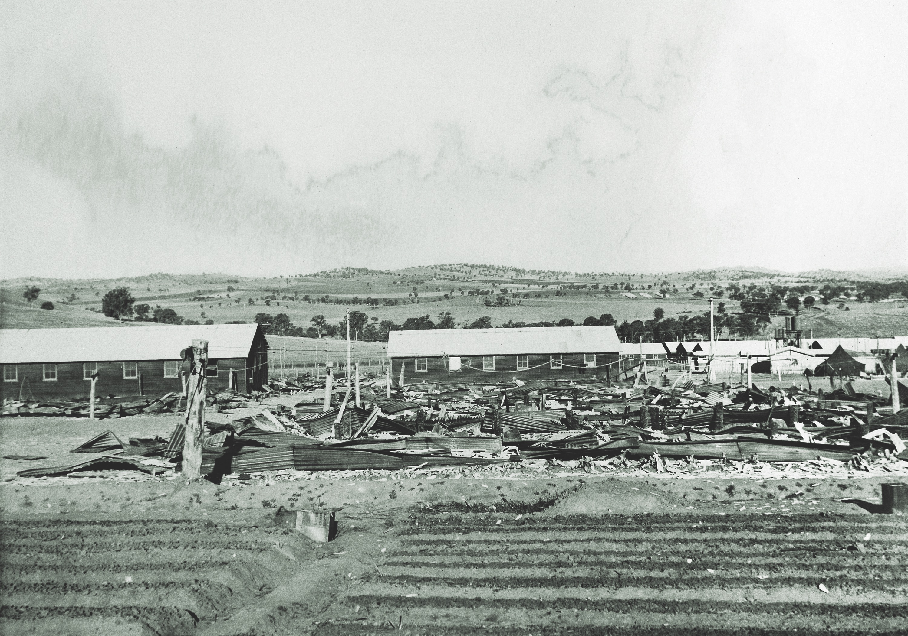 Several of the 18 sleeping huts intentionally burned by the POWs in B Compound still smolder the morning after the attempted escape. The prisoners also torched two other buildings within the compound. (Australian War Memorial)
