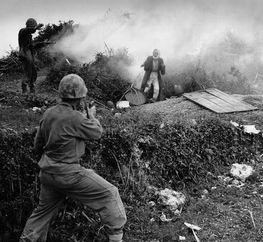 A Japanese soldier surrenders to Marines after being flushed out from a  cave by a smoke grenade. (Department of Defense)