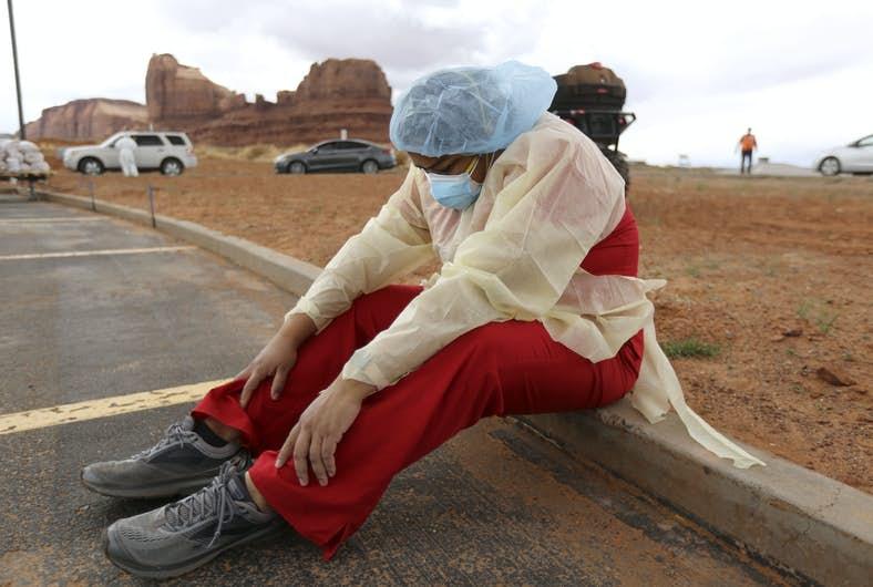 A Navajo health worker takes a brief break as vehicles line up for Covid-19 testing outside of the Monument Valley health center in Utah last month. (Kristin Murphy/AP)