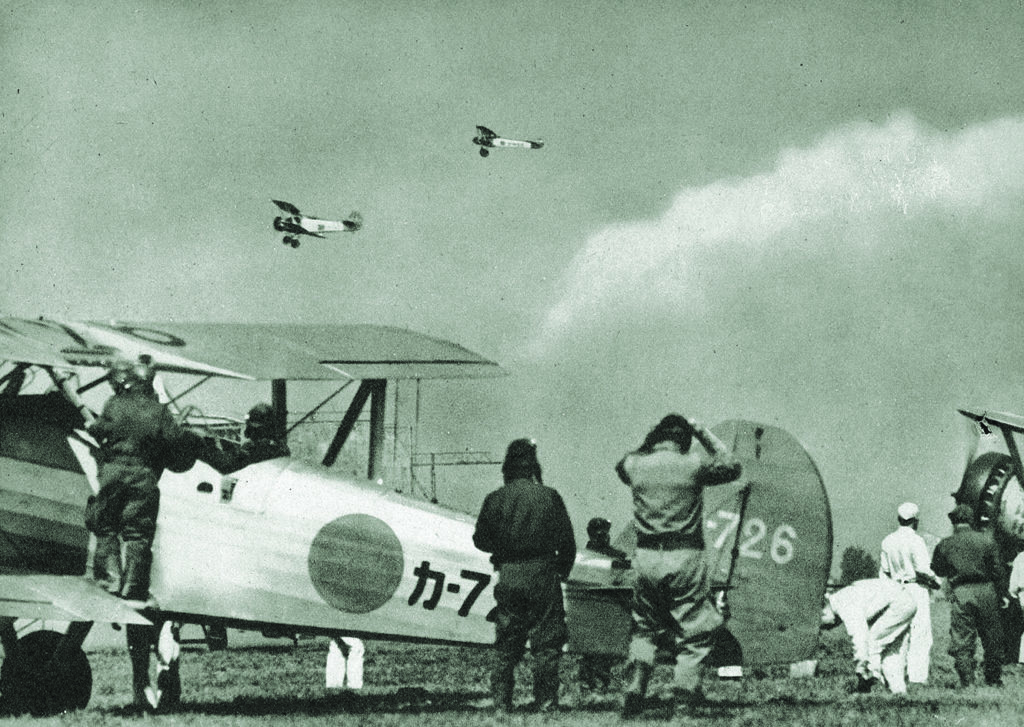 Trainees at Kasumigaura Naval Air School, here in 1938, watch as fellow students take biplane training aircraft through their paces. (The Mainichi Newspapers/AFLO)