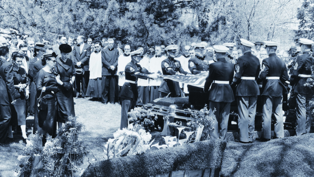 Jean McCarthy, in black hat, and other mourners in St. Mary's cemetery as a Marine honor guard removes the flag from the late legislator's coffin. (Wisconsin Historical Society Image No. 48247)