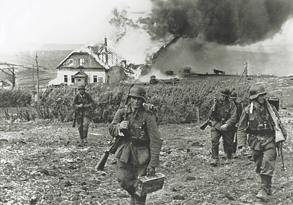 Like the S.S., German Army troops committed war crimes on the Eastern Front. Here, German soldiers smile as they walk away from burning a civilian homestead in Russia. / Ullstein Bild via Getty Images