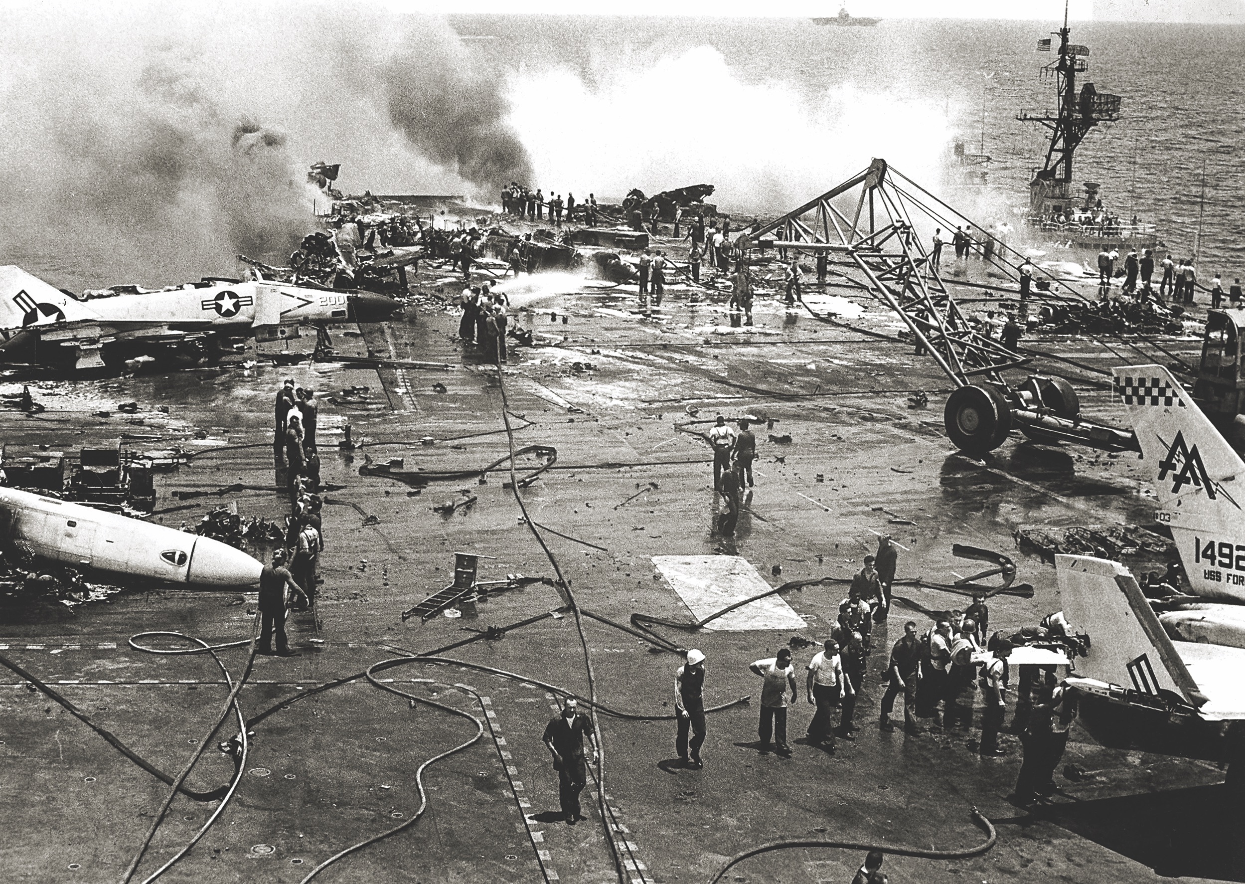 Devastation and debris are strewn across the deck of the Forrestal in the aftermath of an accidental rocket explosion on the bridge in July 1967. / U.S. Navy