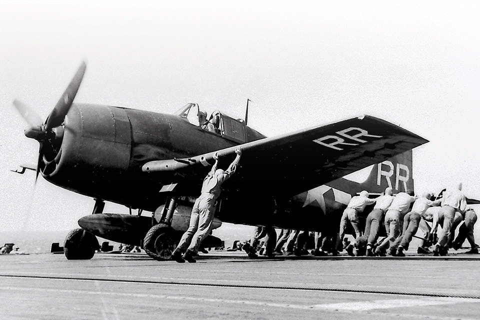 Deck crewmen reposition a F6F-5 Hellcat of fighter squadron VF-88 after it burst a tire while landing on the carrier Yorktown. (National Archives)