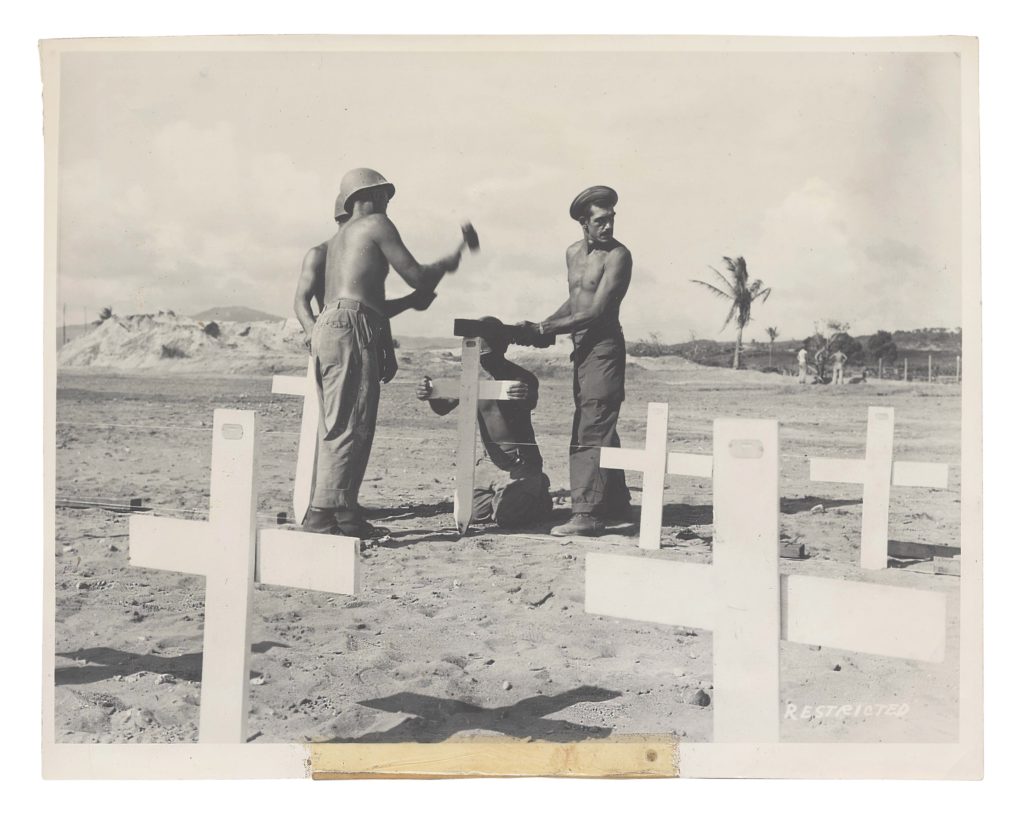 A Graves Registration Service team pounds newly painted crosses into the ground at a 27th Division graveyard on Saipan. (The New York State Military Museum)