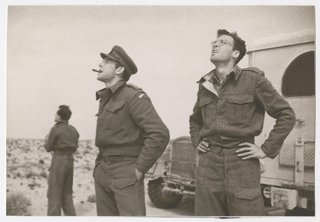 AFS men watch a dogfight in the Tunisian sky. “I saw the sand lift and snap in a sprinkle of machine gun bullets,” Milne wrote after enemy Stukas suddenly appeared overhead. (Courtesy of the Archives of the American Field Service and AFS Intercultural Programs (AFS Archives))