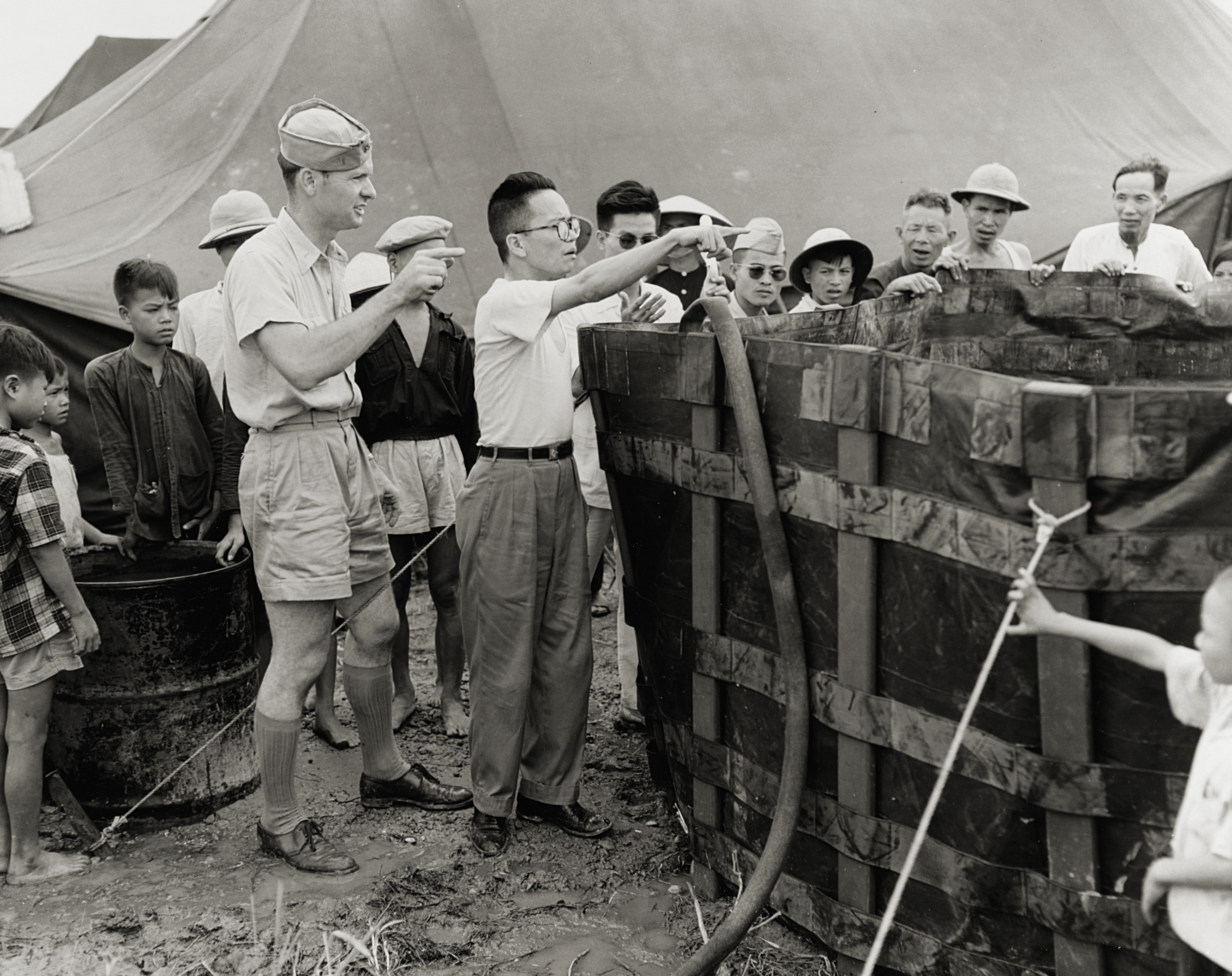 Thomas Dooley, a U.S. Navy doctor, provides instruction on water tanks at a camp in Haiphong, North Vietnam. / US Navy