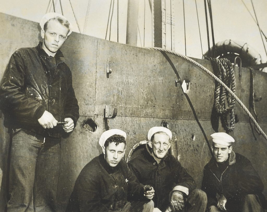 Four of Jack Rowe’s crewmates gather for a photo aboard their LCM after D-Day. The damage behind them is from the shell that killed Rowe. (Courtesy of the National D-Day Memorial Foundation)