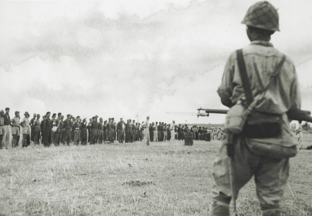 Ultimately, the retreat to Bataan proved a dead end; here, a Japanese guard watches over American and Filipino prisoners captured there. (Keystone/Hulton Archive/Getty Images)