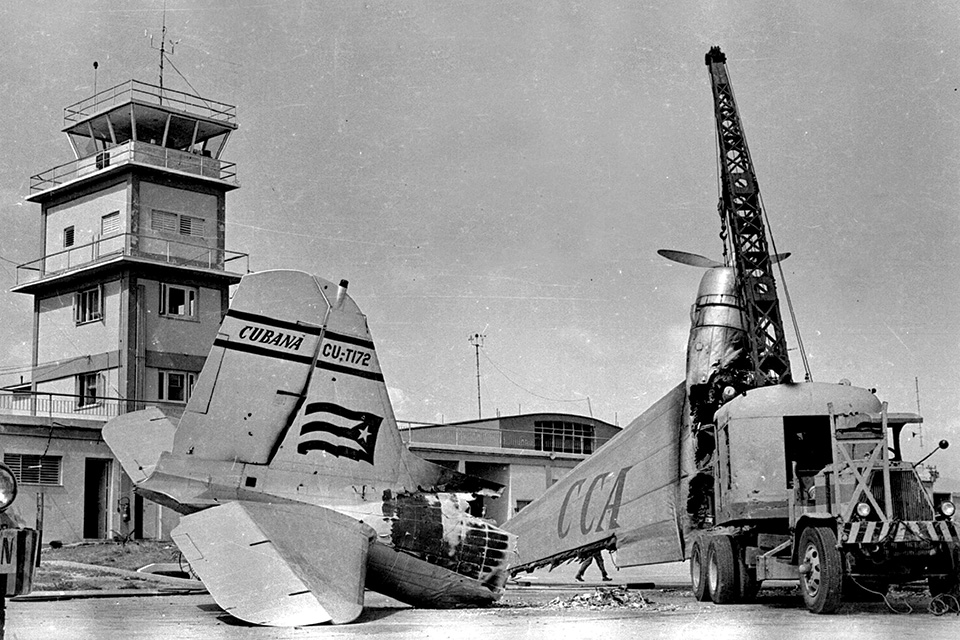 On April 15, 1961, during the abortive Bay of Pigs operation, Cuban exile Gustavo Ponzoa destroyed this DC-3, which he had once flown for Cubana Airlines. Here Cuban workers remove the wreckage at Santiago de Cuba’s air base. (Gilberto Ante/Roger Viollet via Getty Images)