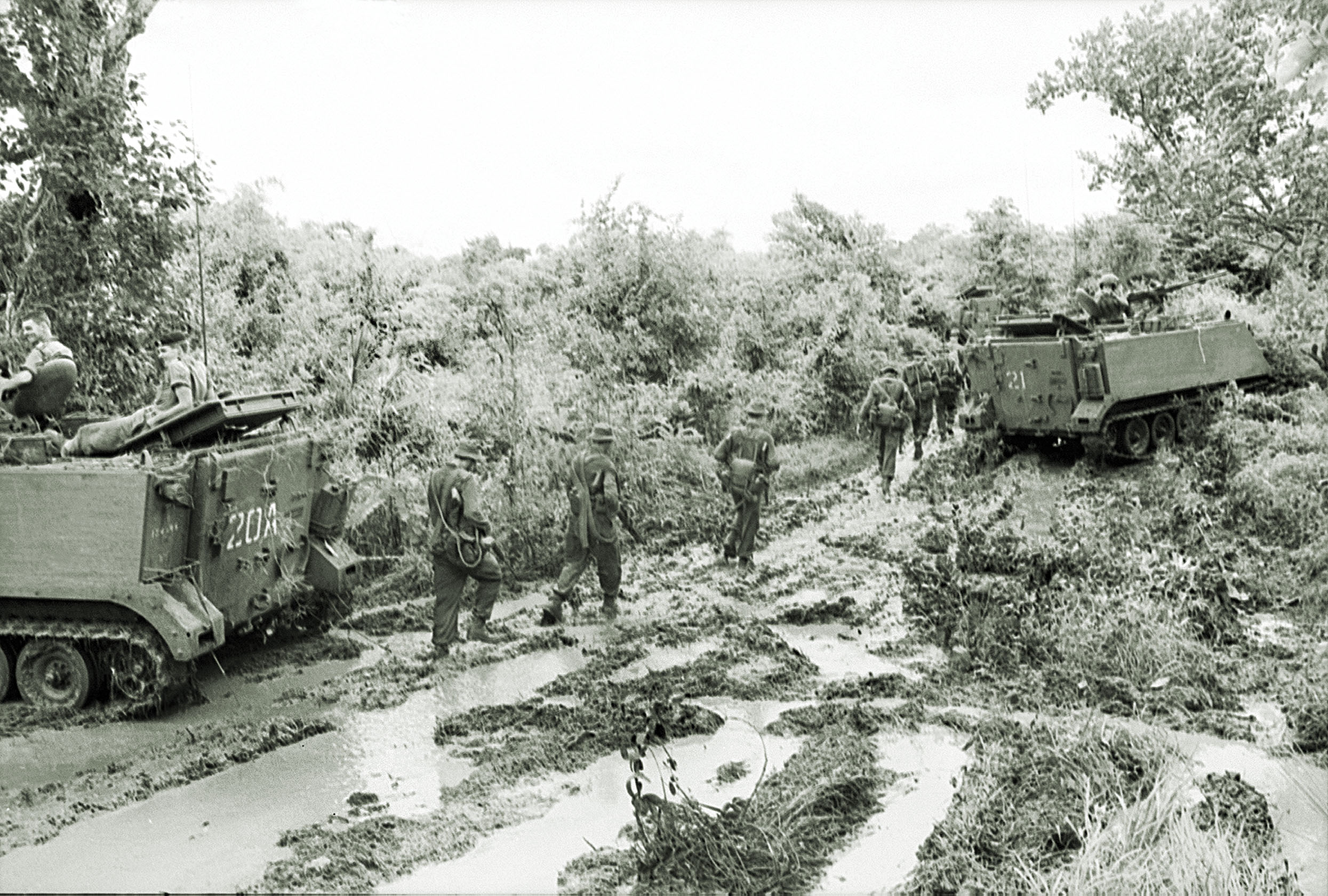 Soldiers of the 6th Battalion pursue a fleeing Viet Cong force on Aug. 19, 1966, the day after the Long Tan battle, fought in heavy rain and thick mud that bogged down men and equipment. / Australian War Memorial