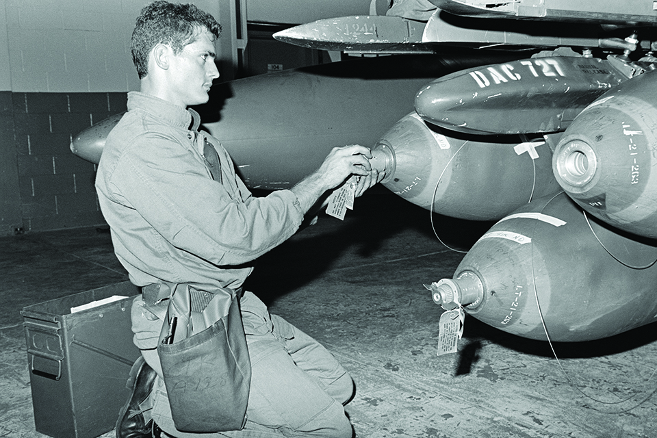 Sergeant Anthony DeBerardinis installs fuzes on M117 bombs carried by a McDonnell F-4E of the 347th Tactical Fighter Wing. (U.S. Air Force)